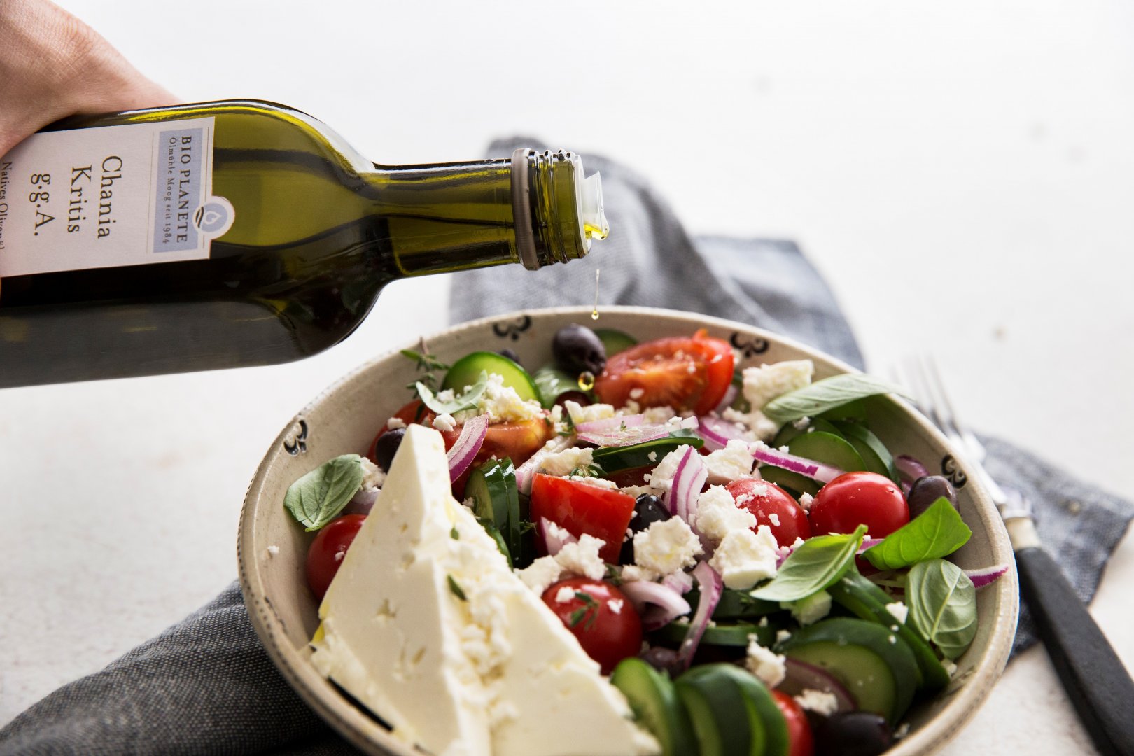 Griechischer Salat mit Feta Käse wird übergossen mit kretischem BIO PLANETE Olivenöl